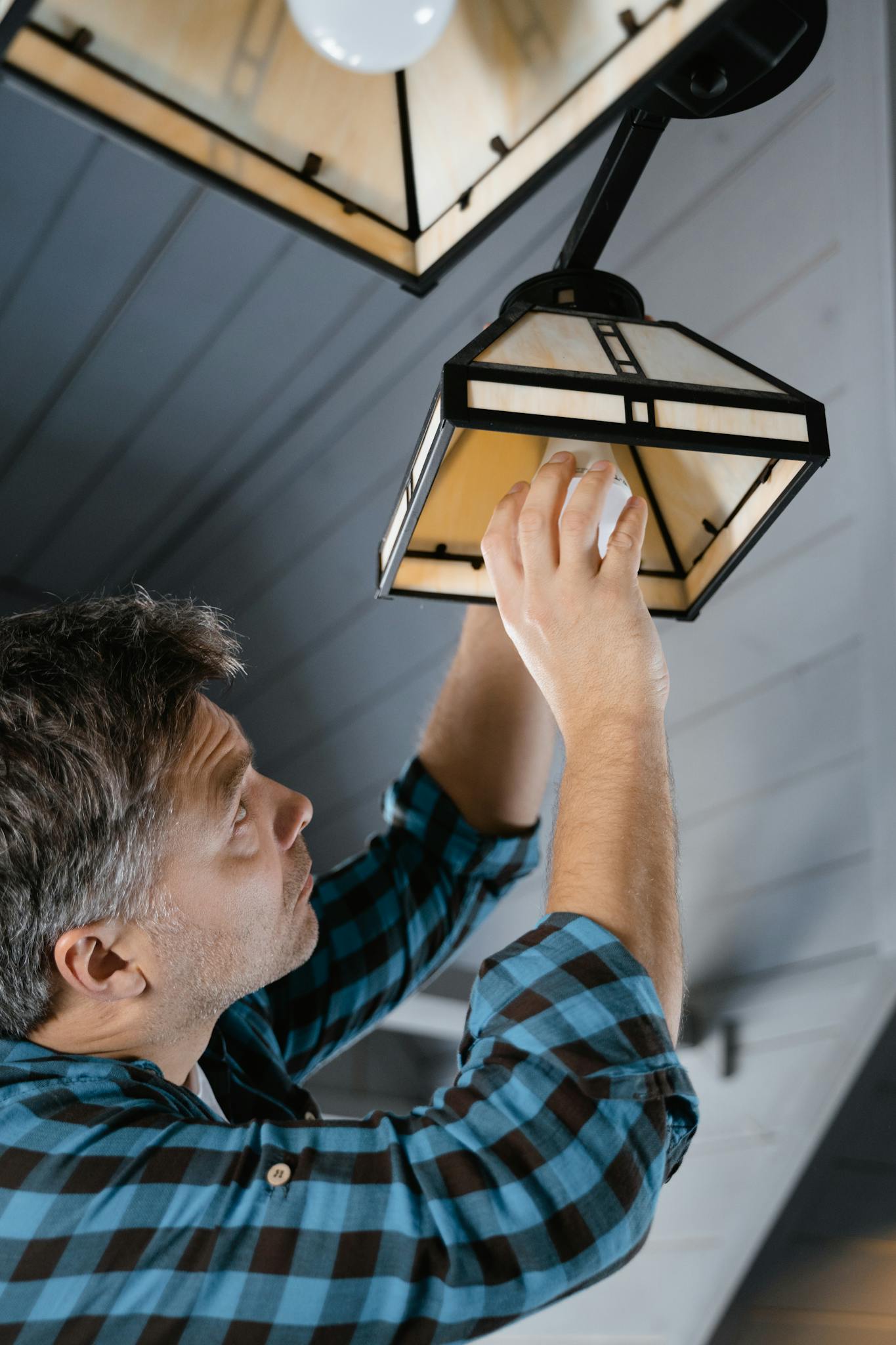 Man In Plaid Shirt Fixing A Pendant